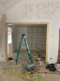 a ladder is in the middle of a room with construction materials around it and tools on the floor