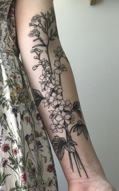 a woman's arm with flowers on it, and the tattoo is done in black ink