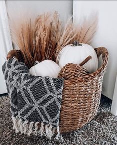 a basket filled with white pumpkins sitting on top of a carpet next to a door