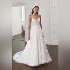 a woman in a white wedding dress standing on a wooden floor with her hands behind her back