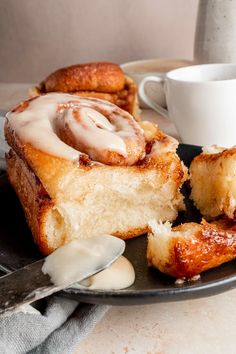 a plate topped with cinnamon rolls next to a cup of coffee