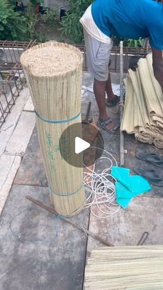 a man standing next to a tall bamboo basket on top of a sidewalk with other items around him