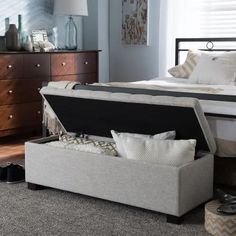 a bed sitting on top of a carpeted floor next to a dresser and footstool