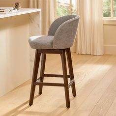 a gray bar stool sitting on top of a hard wood floor next to a window