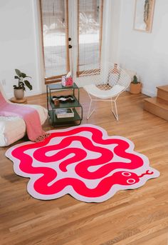 a red and white rug sitting on top of a wooden floor next to a chair