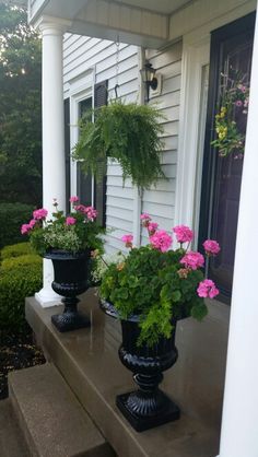 three black vases with pink flowers on the front porch