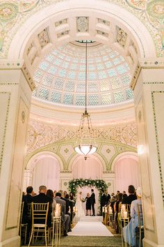 a couple getting married at the end of their wedding ceremony in an ornately decorated building