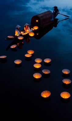 people floating in the water with lit candles