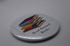 a white button with books on it sitting on a table next to a pen and pencil