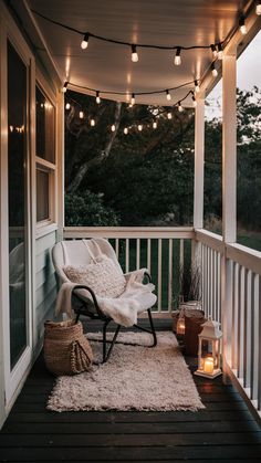 a porch with lights strung over it and a chair on the front porch, next to a rug