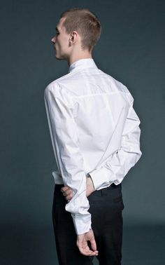 a man in a white shirt and black pants with his back turned to the camera