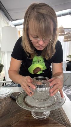 a woman is looking at a glass dish on a table