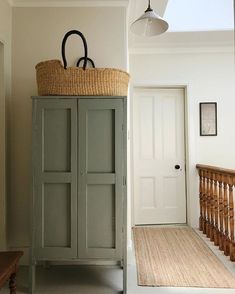 a cabinet with a basket on top of it next to a stair case in a house