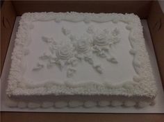 a square cake with white frosting flowers in a box