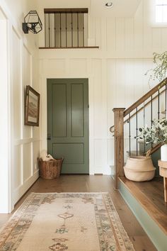 an entryway with a rug, basket and stairs leading to the second floor area