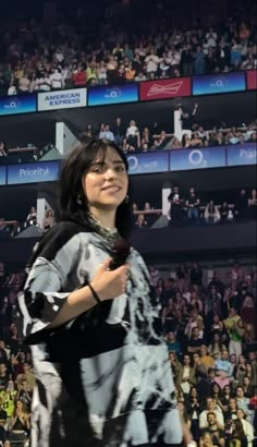 a woman standing in front of a crowd holding a cell phone