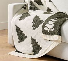 a white couch with a green and white christmas tree blanket on it's back