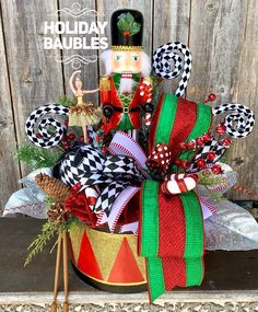 a holiday nutcracker arrangement in a red and green tin can with decorations around it