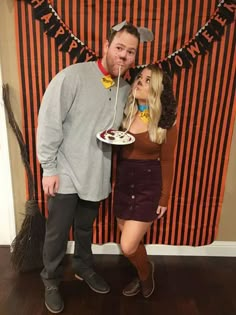 a man and woman standing in front of a halloween banner