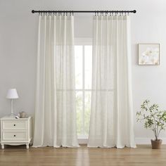 a living room with white curtains and wooden floors