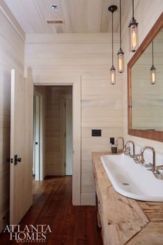 a bathroom with two sinks and three lights hanging from the ceiling over it's wood flooring