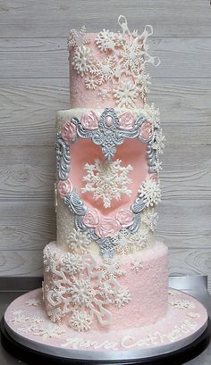 a three tiered cake with pink frosting and silver decorations