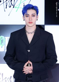 a young man with blue hair and piercings on his chest wearing a black suit