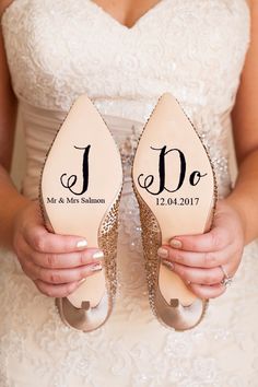 a bride holding her wedding shoes with i do written on them