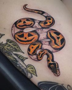 an orange and black snake tattoo on the back of a woman's thigh,