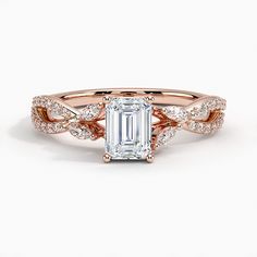 a rose gold engagement ring with an emerald center stone and two diamonds on the band