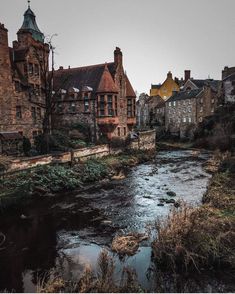 a river running through a small town next to tall brick buildings with towers on top