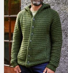 a man standing in front of a building wearing a green knitted cardigan sweater