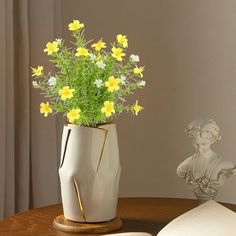 a vase filled with yellow flowers on top of a table next to an open book