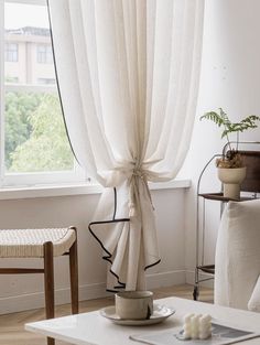 a living room with white furniture and curtains