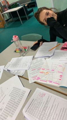 a woman sitting at a table with lots of papers on it