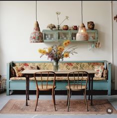 two chairs and a table in front of a wall with vases on the shelves