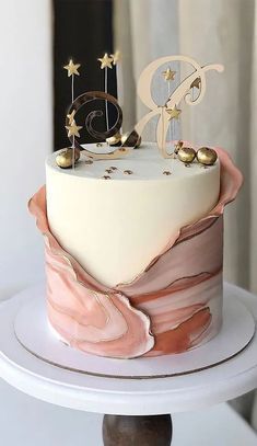 a white and pink cake with gold decorations