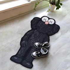 a pair of shoes sitting on the floor next to a door mat that looks like a bear