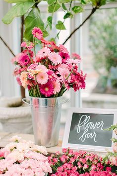 pink and white flowers are on display in a metal bucket next to a sign that says flower year