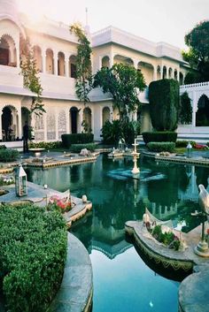 an outdoor garden with fountains and flowers in the center, surrounded by white buildings on either side