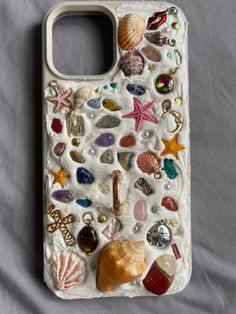 a cell phone case with shells and seashells on the back, sitting on a bed