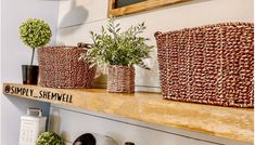 three baskets are sitting on a shelf with plants in them