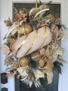 a wreath with gold and white ornaments hanging from the front door, decorated with greenery