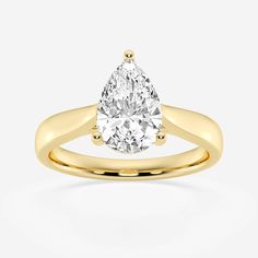 a yellow gold engagement ring with a pear shaped diamond in the center, on a white background