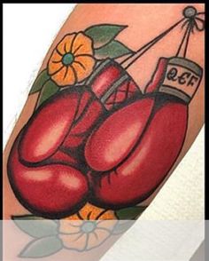 a tattoo with two red boxing gloves on it's arm and flowers in the background