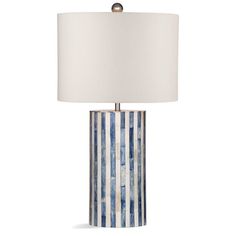 a blue and white striped lamp with a white shade on the top, sitting in front of a white background