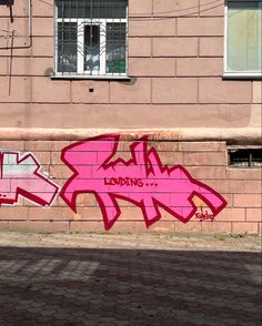 graffiti on the side of a building in front of a red brick wall with windows