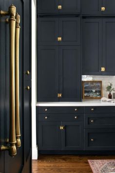 a kitchen with black cabinets and gold pulls on the door knobs is pictured in this image