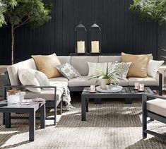 a living room filled with lots of furniture next to a wooden wall covered in greenery