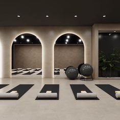 an empty yoga room with black and white mats on the floor, lit by lights